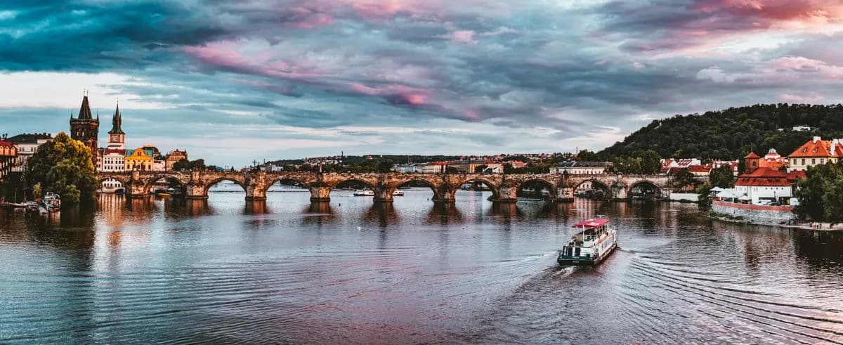 A river boat passing a stone bridge at dusk